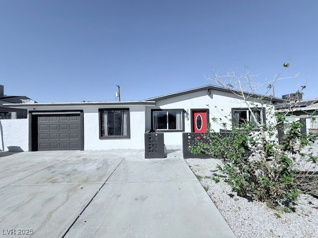 Single story home featuring stucco siding, a garage, and concrete driveway