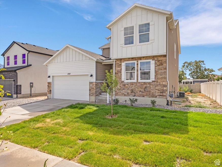 View of front of property featuring board and batten siding, concrete driveway, stone siding, and a garage