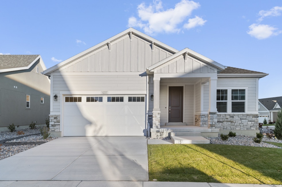 Craftsman-style house featuring stone siding, board and batten siding, driveway, and an attached garage