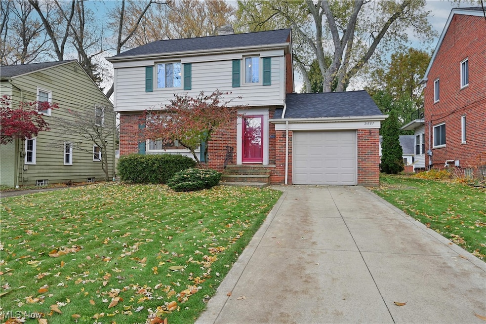 Colonial inspired home featuring brick siding, concrete driveway, a front lawn, and an attached garage