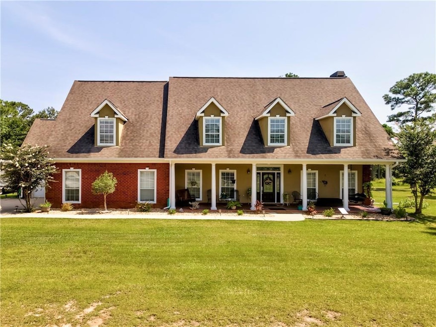 New england style home featuring a front lawn, covered porch, and a shingled roof