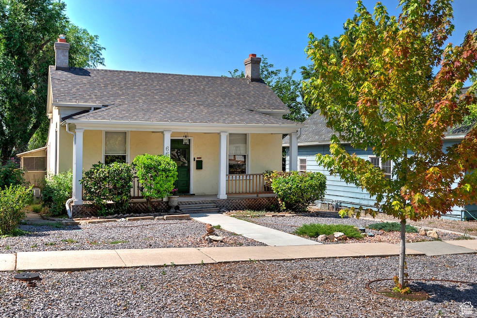 Bungalow with a porch, a chimney, roof with shingles, and stucco siding
