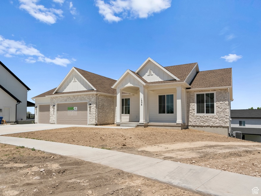 View of front of house with board and batten siding, covered porch, a garage, stone siding, and roof with shingles