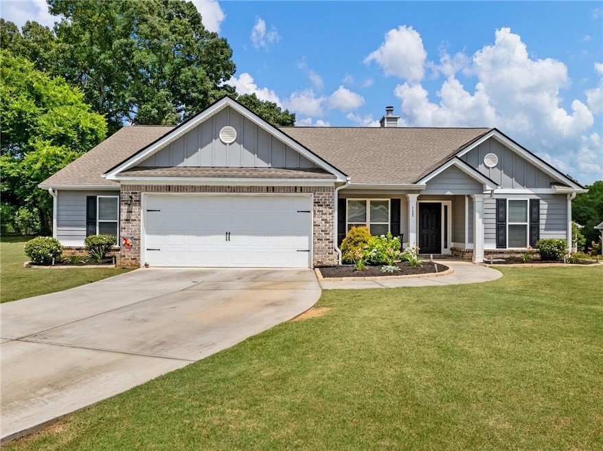 Ranch-style house with a garage, a shingled roof, board and batten siding, brick siding, and concrete driveway