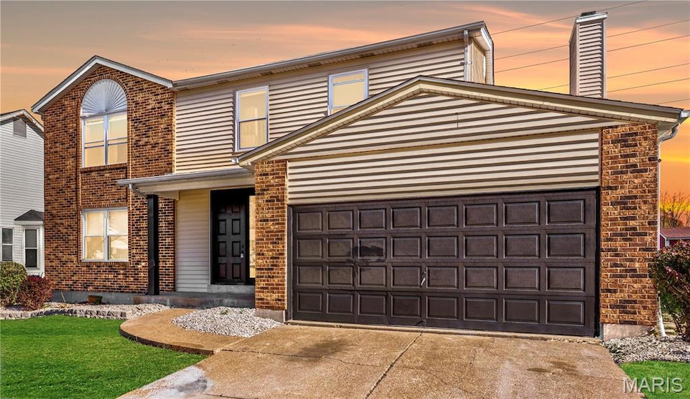 Traditional home with brick siding, driveway, a chimney, a lawn, and a garage