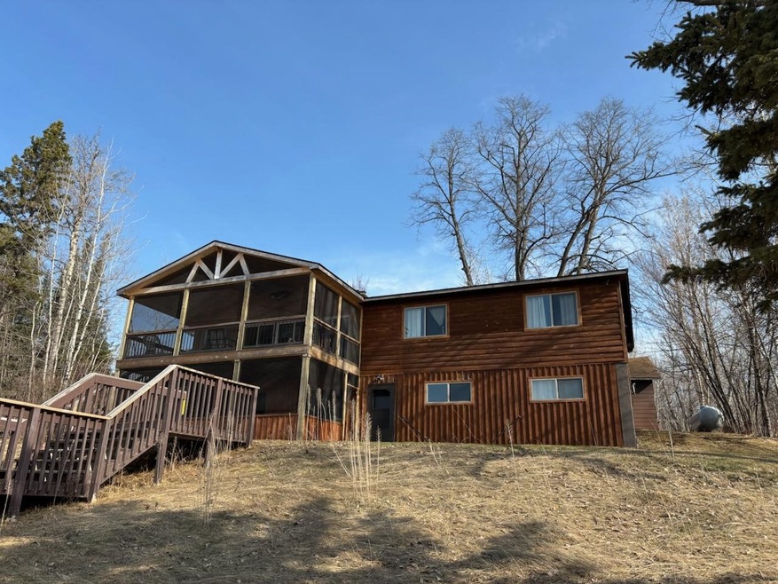 Back of property featuring a wooden deck, a sunroom, and stairs