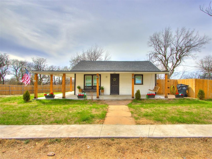 View of front of house with a porch, a front lawn, and fence