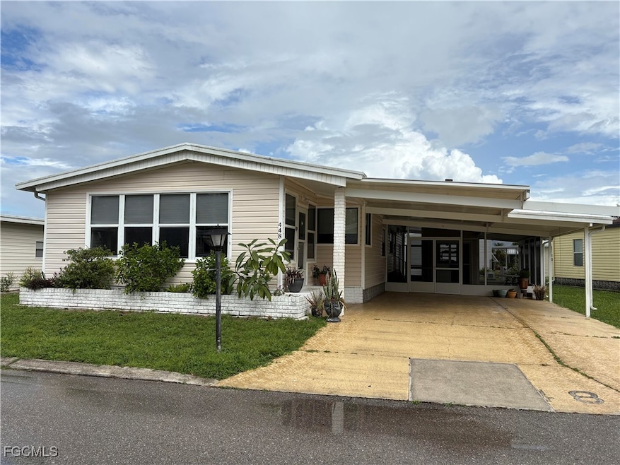 View of front of home featuring concrete driveway, a front lawn, an attached carport, and a sunroom