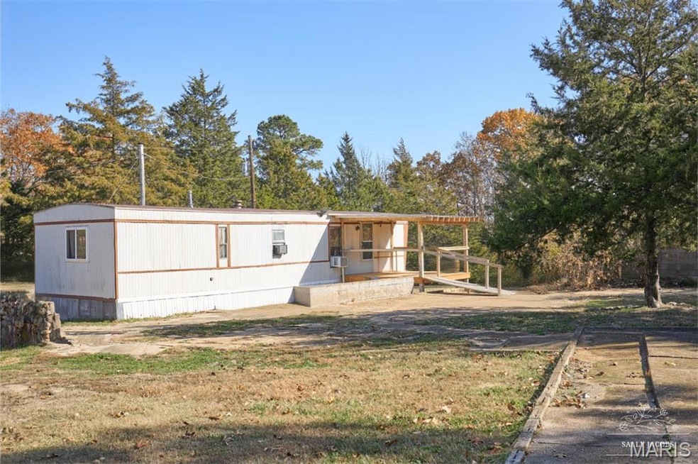 View of front facade featuring a porch, view of wooded area, and a front lawn