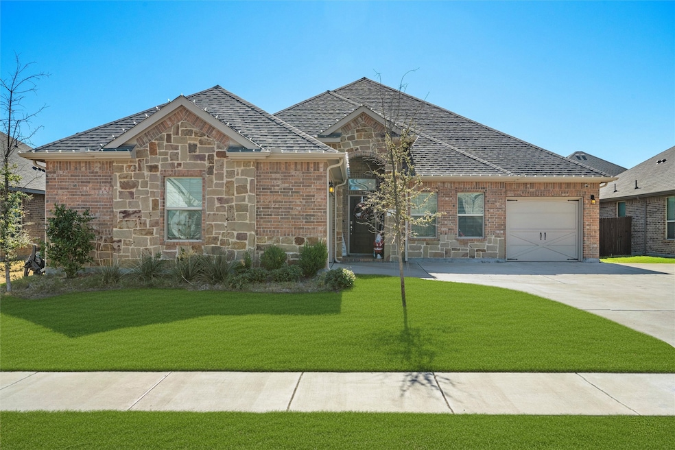 View of front facade with stone siding, a front lawn, concrete driveway, a garage, and brick siding