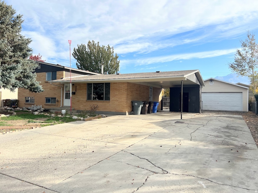 View of front of home with brick siding, an outdoor structure, a detached garage, and driveway