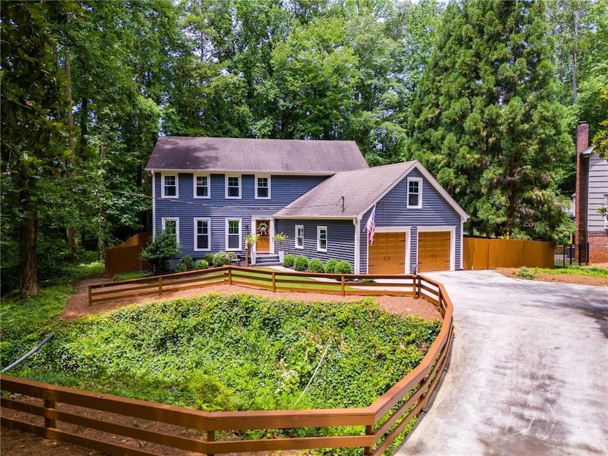 Colonial home featuring a garage, concrete driveway, and a shingled roof