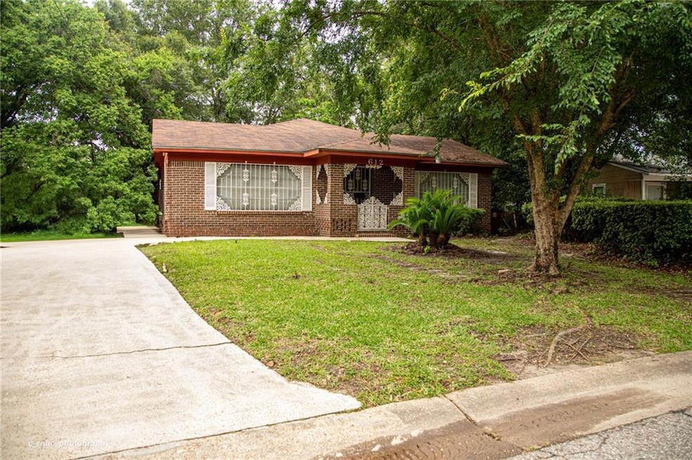 View of front of property featuring brick siding, a front lawn, concrete driveway, and covered porch