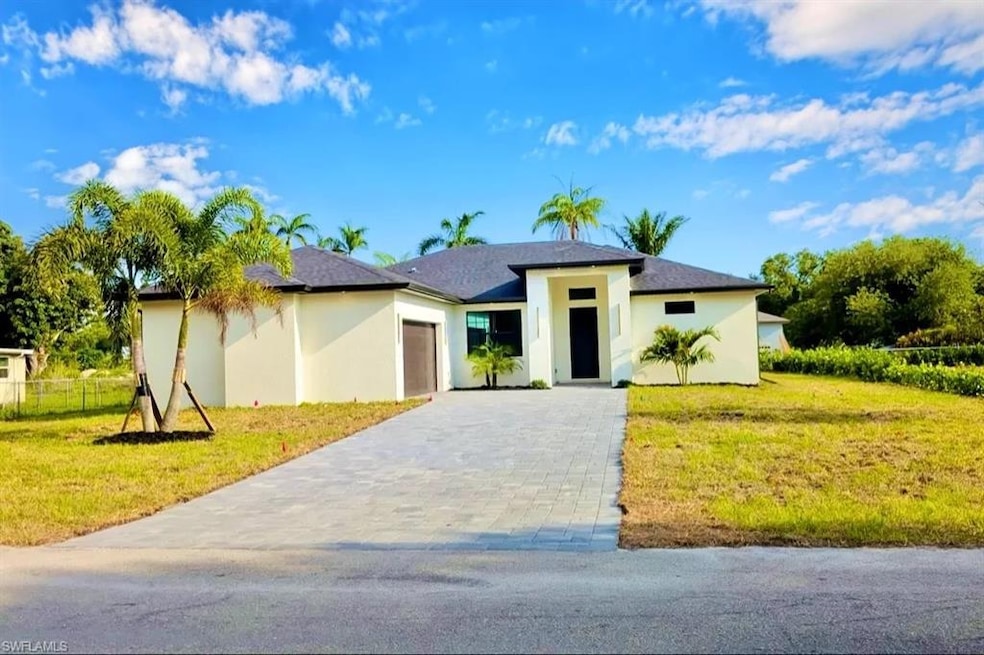 Prairie-style house with an attached garage, stucco siding, and decorative driveway