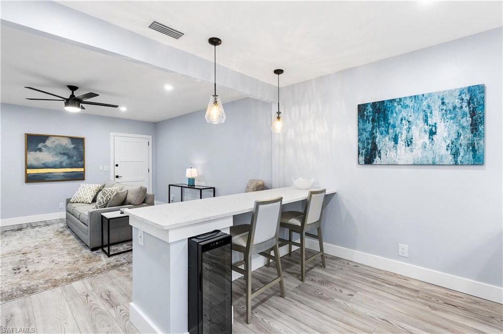 Kitchen featuring visible vents, light wood-style flooring, wine cooler, a peninsula, and light countertops