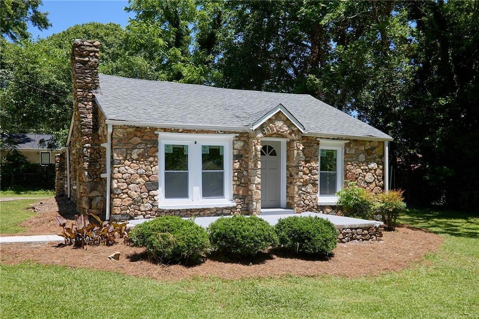 View of front of property with stone siding, a front yard, and a chimney