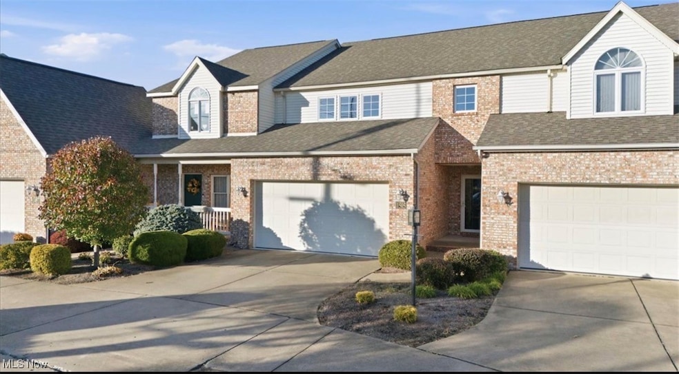 Traditional-style house featuring concrete driveway, a garage, roof with shingles, and brick siding