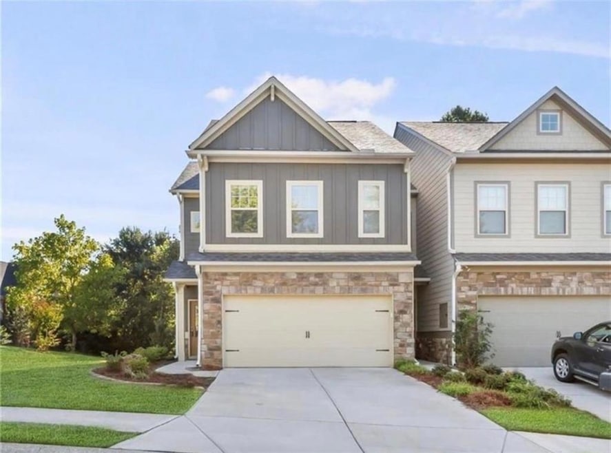 Craftsman inspired home with stone siding, board and batten siding, driveway, a front lawn, and an attached garage