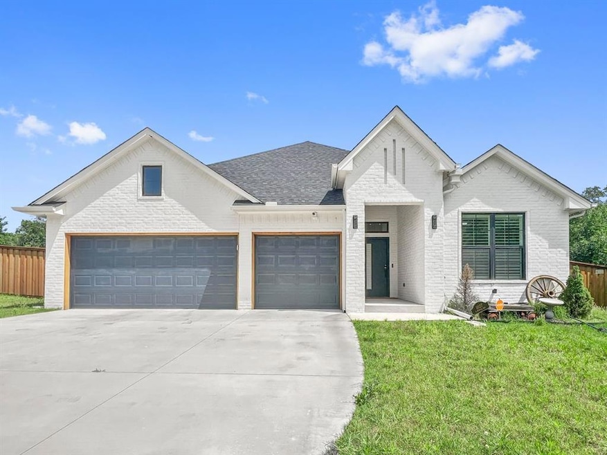 View of front of property featuring brick siding, concrete driveway, an attached garage, and a shingled roof