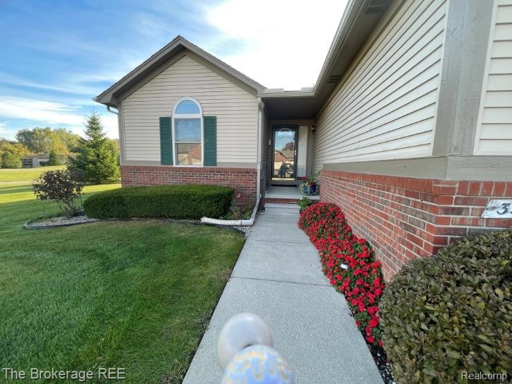 View of exterior entry with a lawn and brick siding