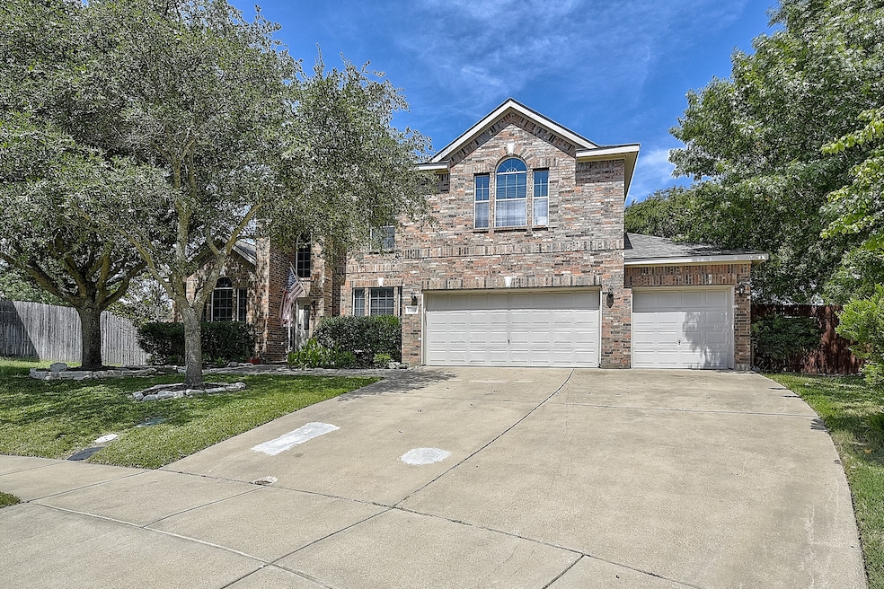 Traditional-style house featuring driveway, an attached garage, stone siding, and brick siding