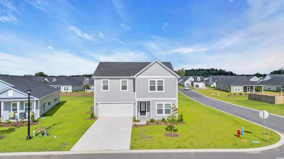 Traditional-style home featuring a residential view, a garage, concrete driveway, and a front yard