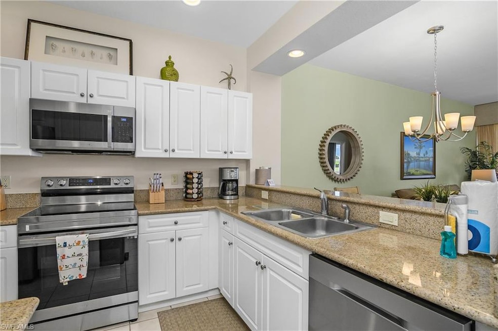 Kitchen featuring recessed lighting, a chandelier, stainless steel appliances, white cabinets, and a sink