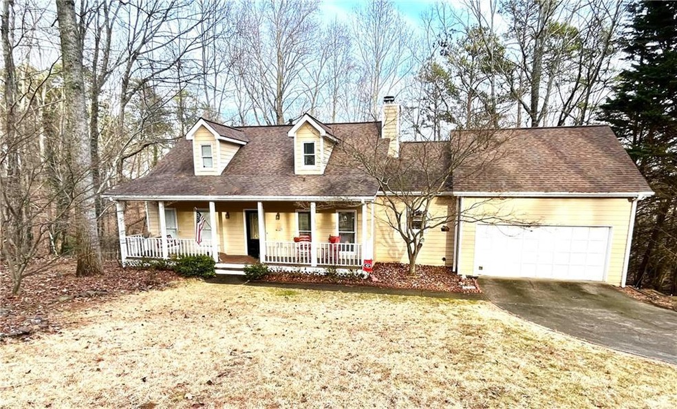 Cape cod-style house featuring a garage and a porc