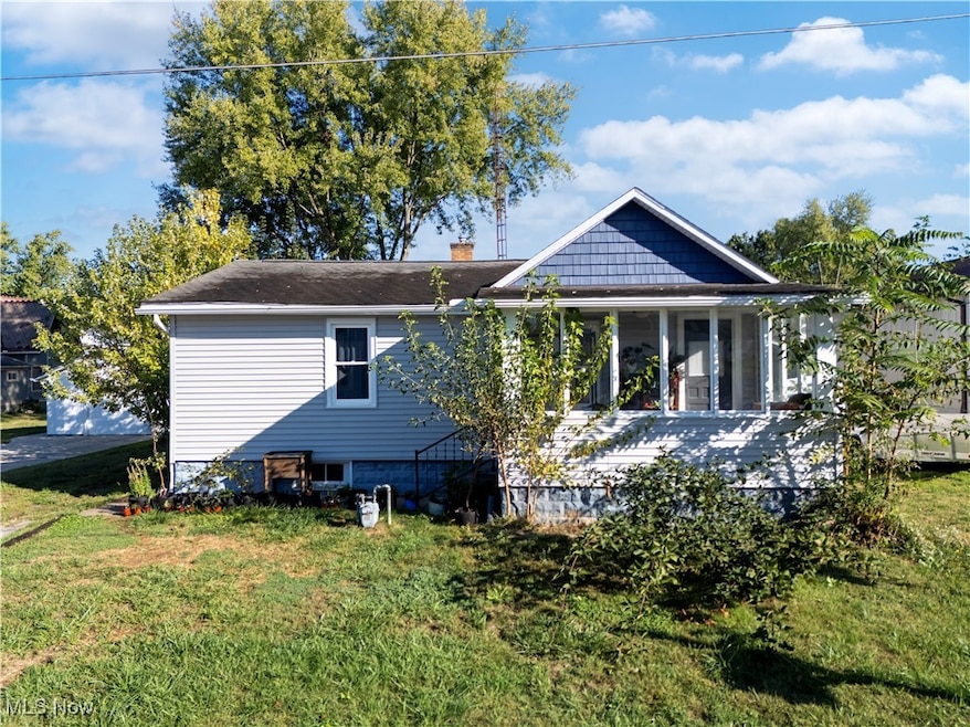 Back of property with a yard, a chimney, and a sunroom