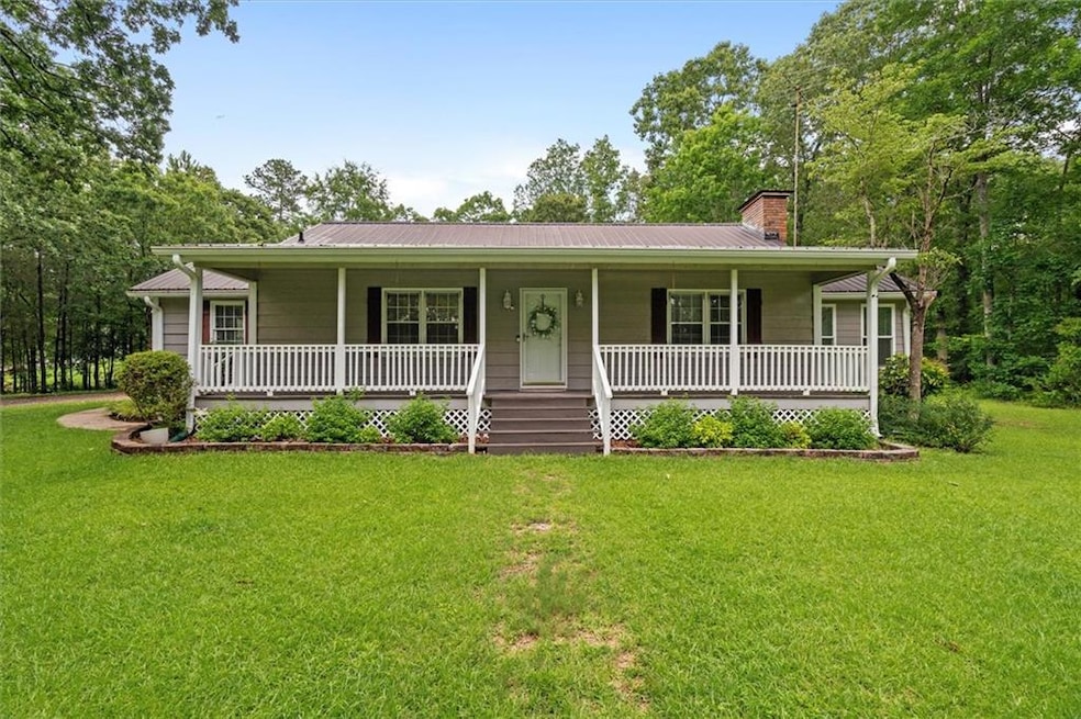 View of front of property featuring a chimney, covered porch, a front lawn, and metal roof