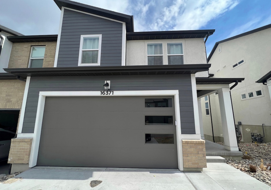 View of front facade featuring a porch, an attached garage, and driveway