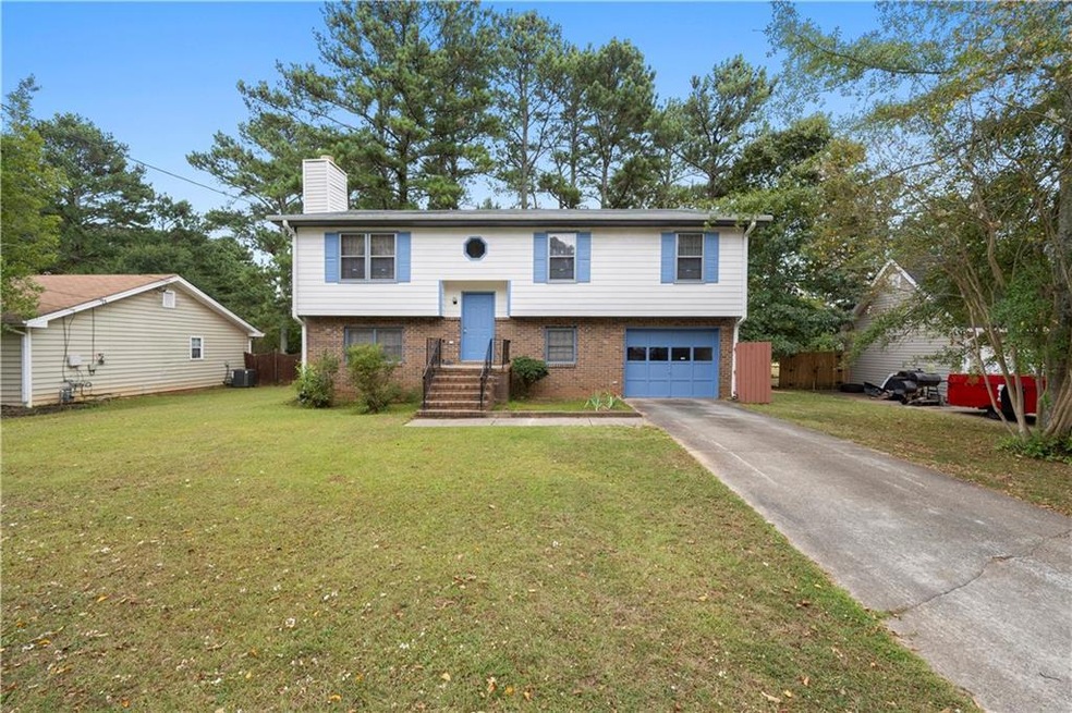 Raised ranch featuring a garage and a front lawn