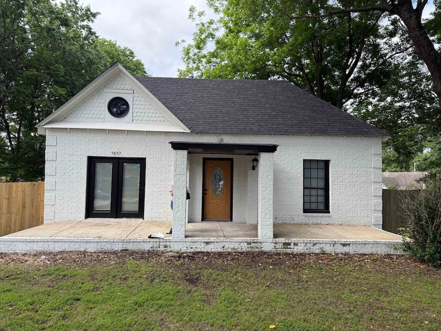 View of front facade with brick siding, a shingled roof, and french doors