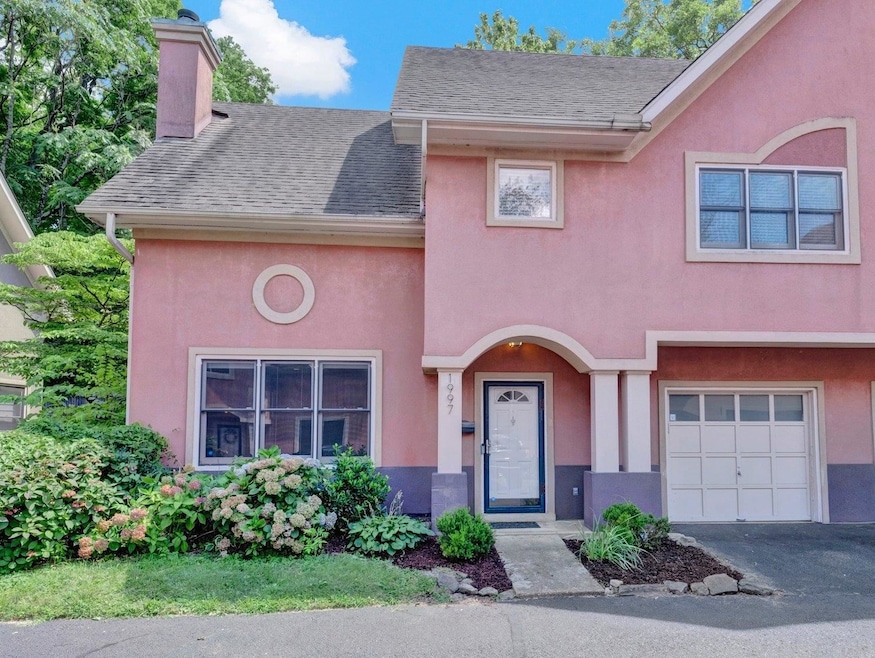Multi unit property featuring stucco siding, a chimney, driveway, an attached garage, and a shingled roof