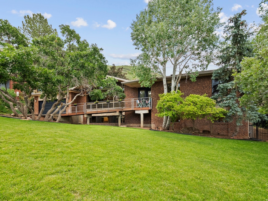 Rear view of house featuring brick siding, a yard, and a deck