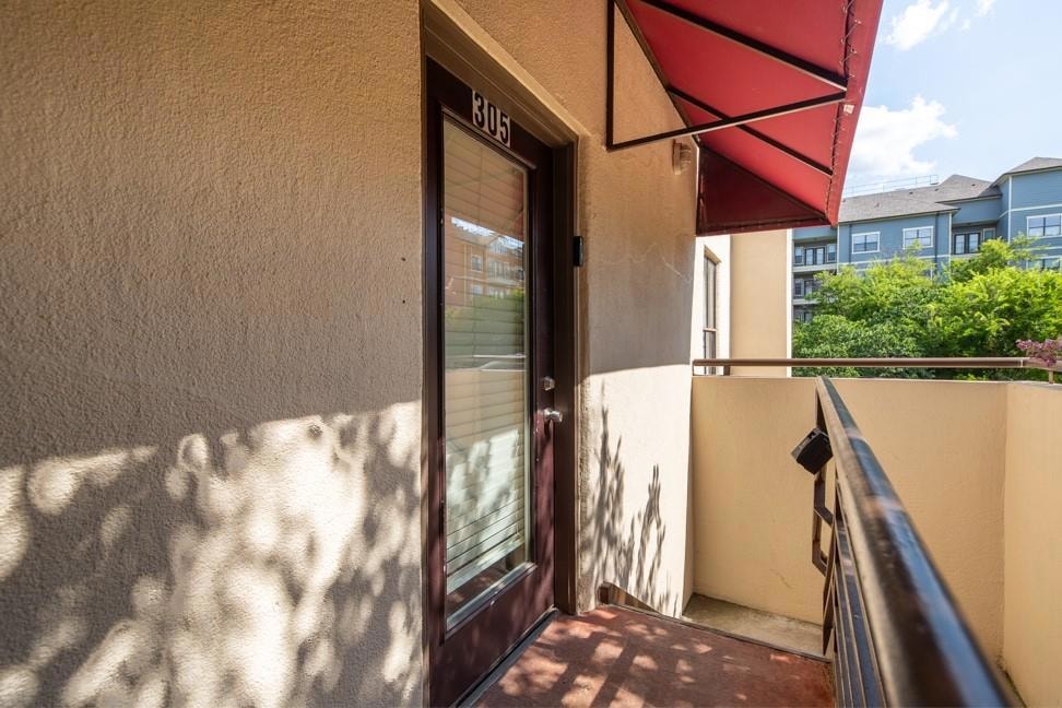 Entrance to property with stucco siding and a balcony