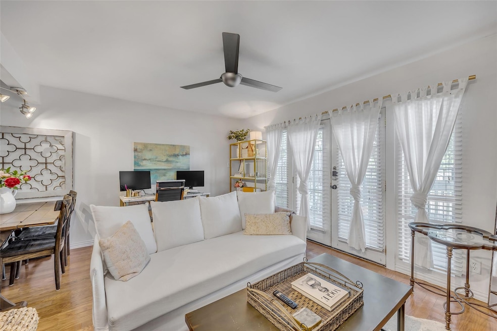 Living room featuring ceiling fan and light wood-