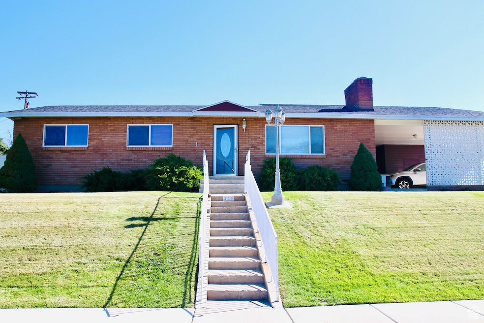 Ranch-style house with brick siding, stairway, a chimney, and a front lawn
