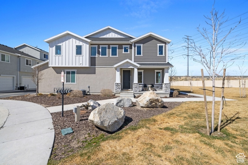 View of front facade featuring stucco siding, board and batten siding, and a front yard