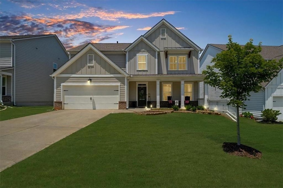 Craftsman-style home featuring board and batten siding, a porch, driveway, a front lawn, and a garage