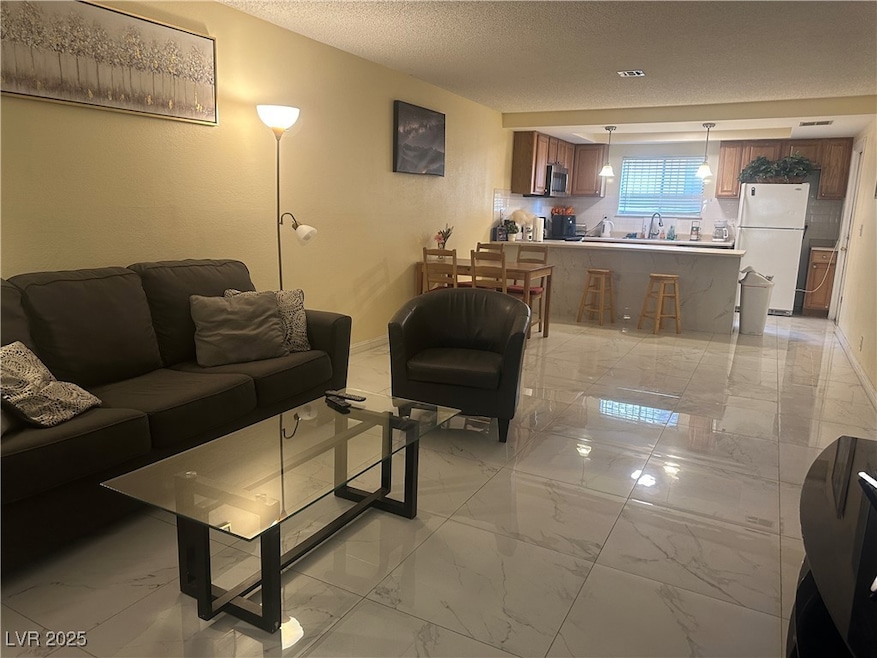 Living area featuring a textured ceiling, marble f