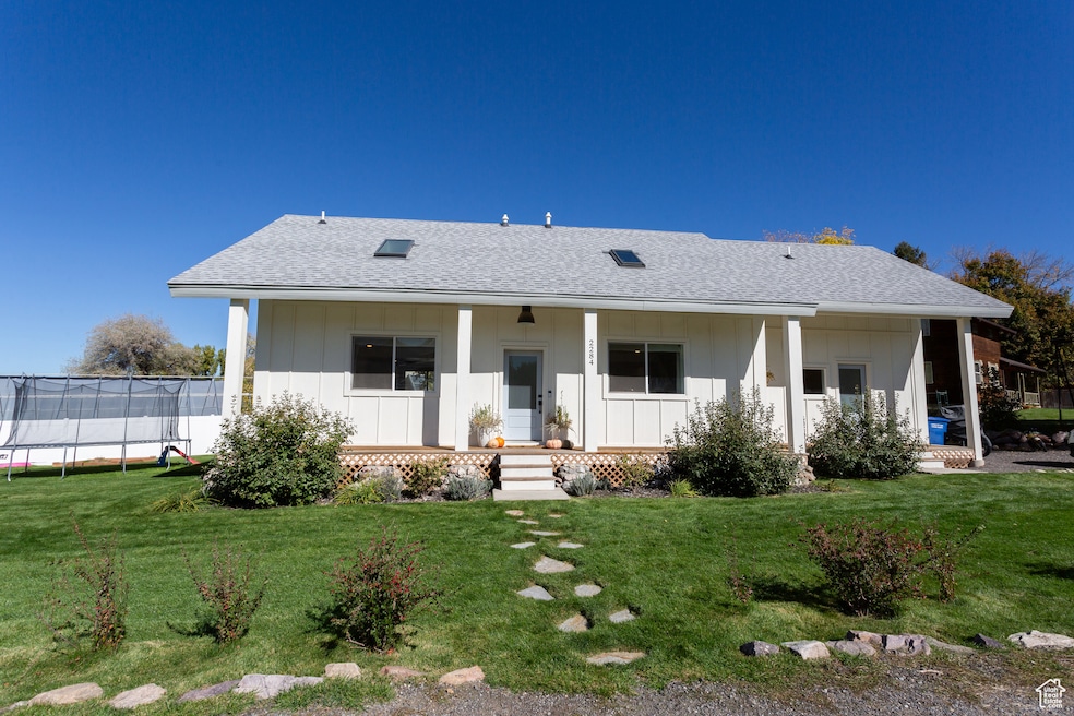 Rear view of property featuring roof with shingles, covered porch, and board and batten siding