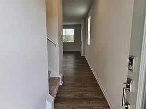 Hallway featuring baseboards and dark wood-style flooring