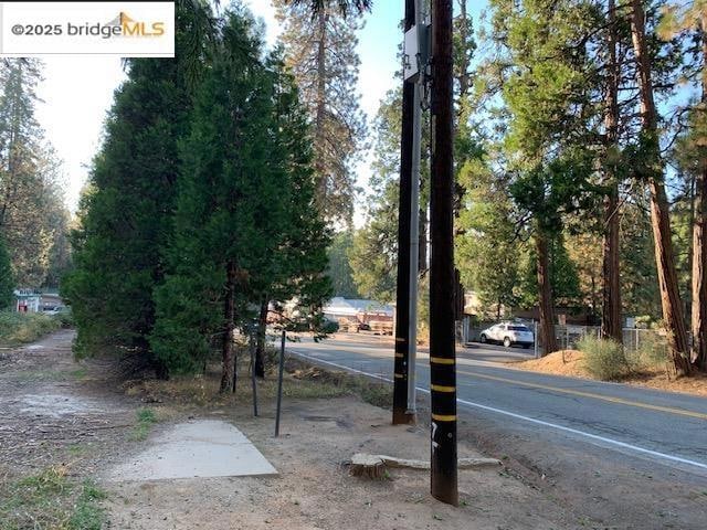 View of asphalt road featuring view of wooded area