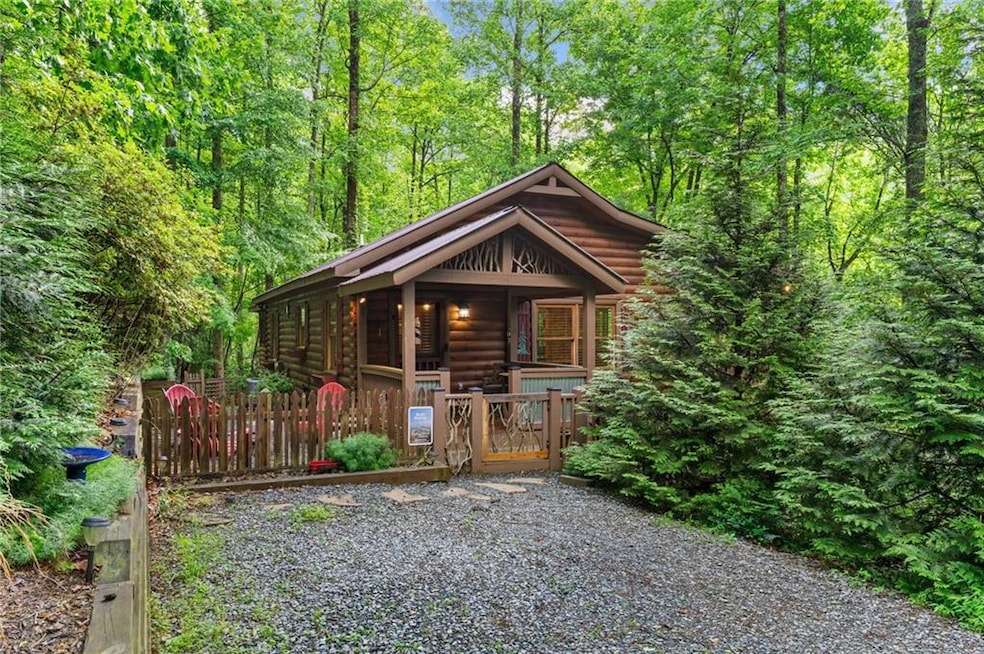 View of front of home with a gate, a porch, and a forest view