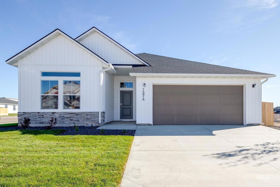 View of front of property featuring stone siding, a front lawn, driveway, board and batten siding, and a garage