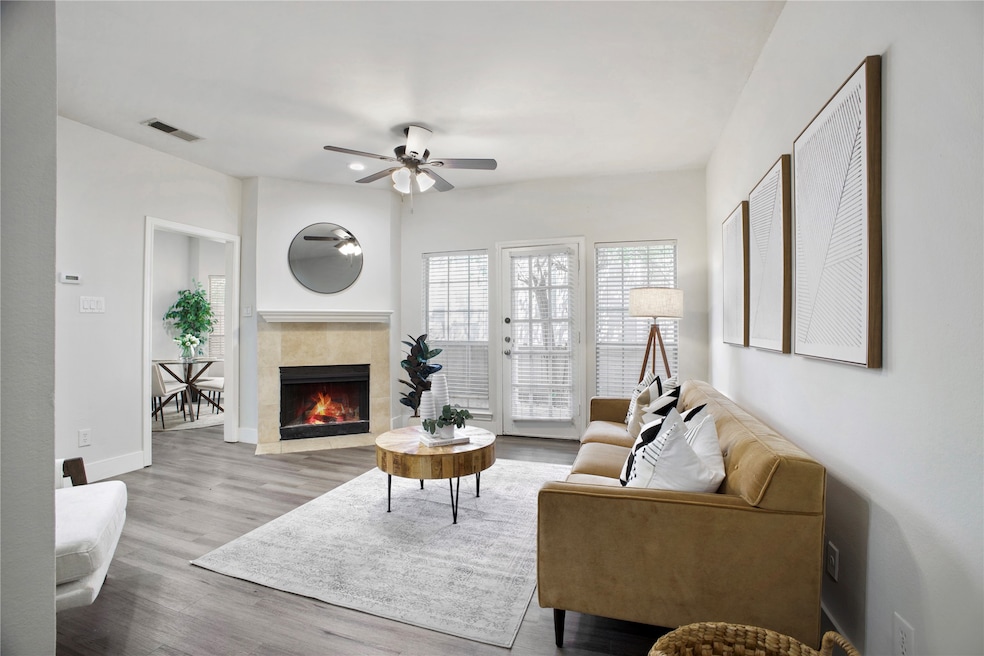 Living room with a fireplace, wood finished floors, and a ceiling fan