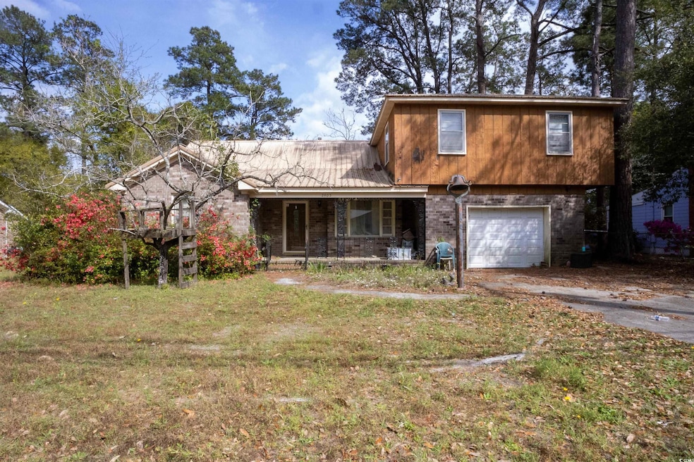 View of front of home featuring driveway, a front yard, covered porch, and a garage