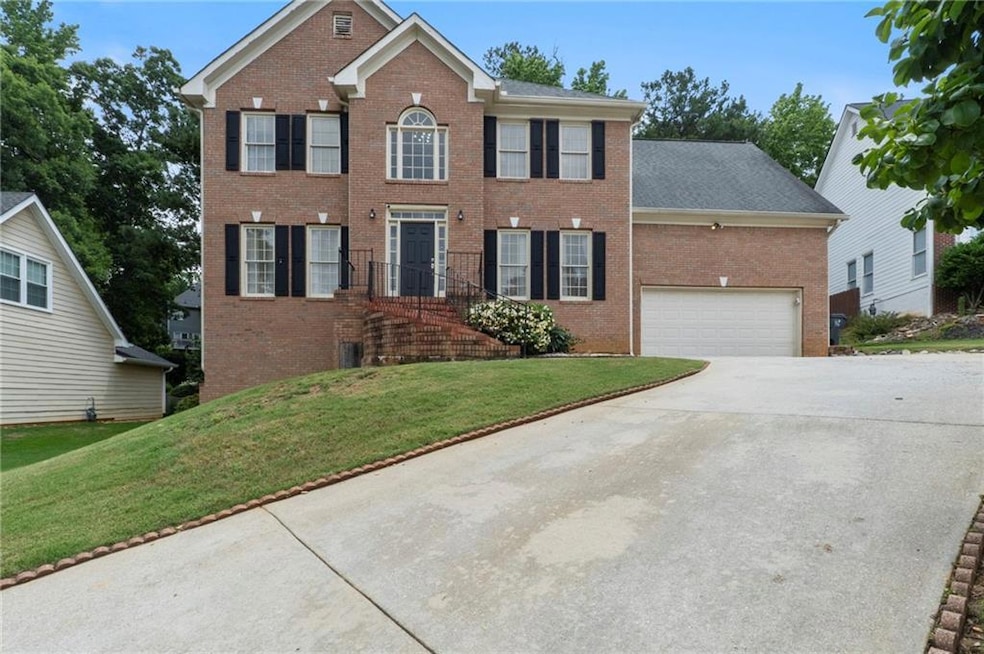 Colonial home with brick siding, driveway, a front yard, and an attached garage