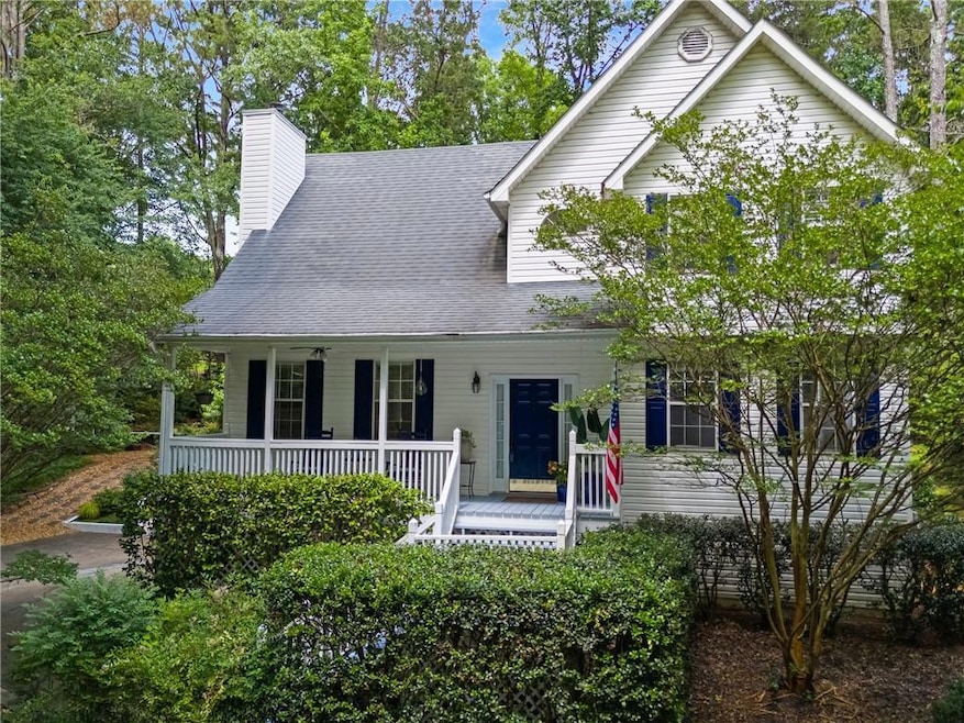 View of front facade featuring covered porch, a chimney, and a shingled roof